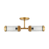 Akurdi 2 Light Bathroom Wall Light in Clear, with two ribbed glass cylinders capped in brass, mounted on a round brass wall plate, shown on a plain white background.