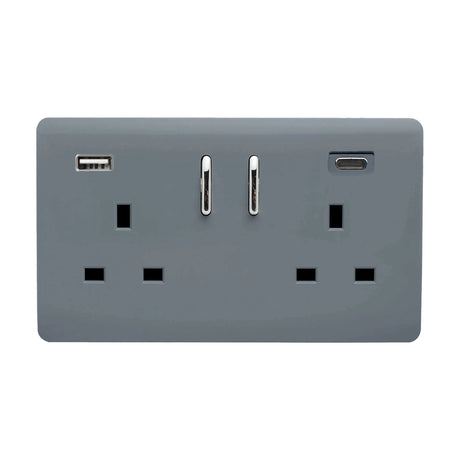 Warm grey screwless double socket with two switched 13A outlets, chrome rockers, and a USB-A/C charging port with chrome trim, shown on a plain background.