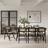 Ashton dining chairs with black ash wood frames and natural cane backs and seats, shown around a black dining table in a light, shiplap-panelled dining room.