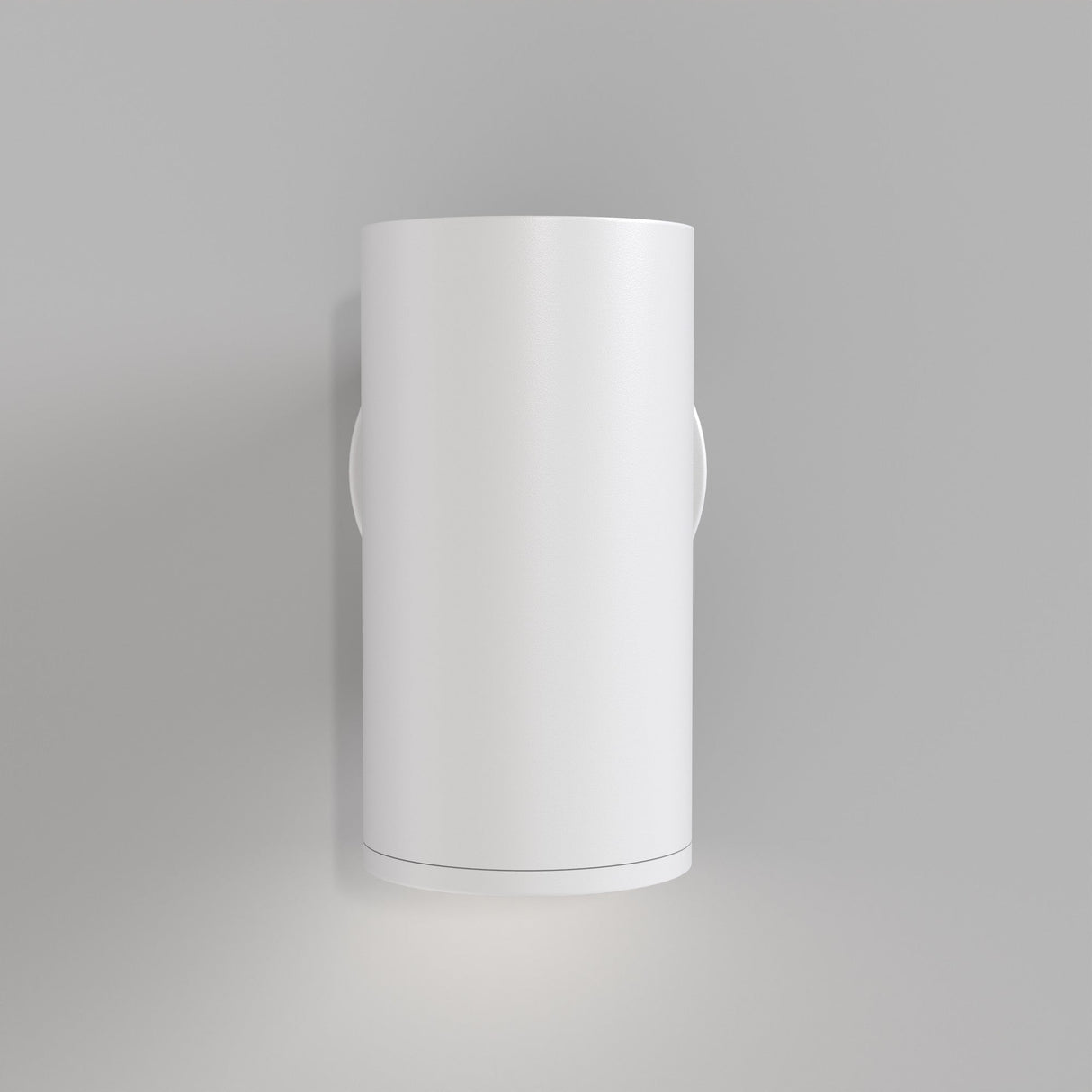 The FOCUS S Down Wall Light - White is a sleek, cylindrical fixture casting light both upward and downward. Mounted on a neutral gray wall, its white finish offers a minimalist aesthetic that enhances any modern industrial decor.