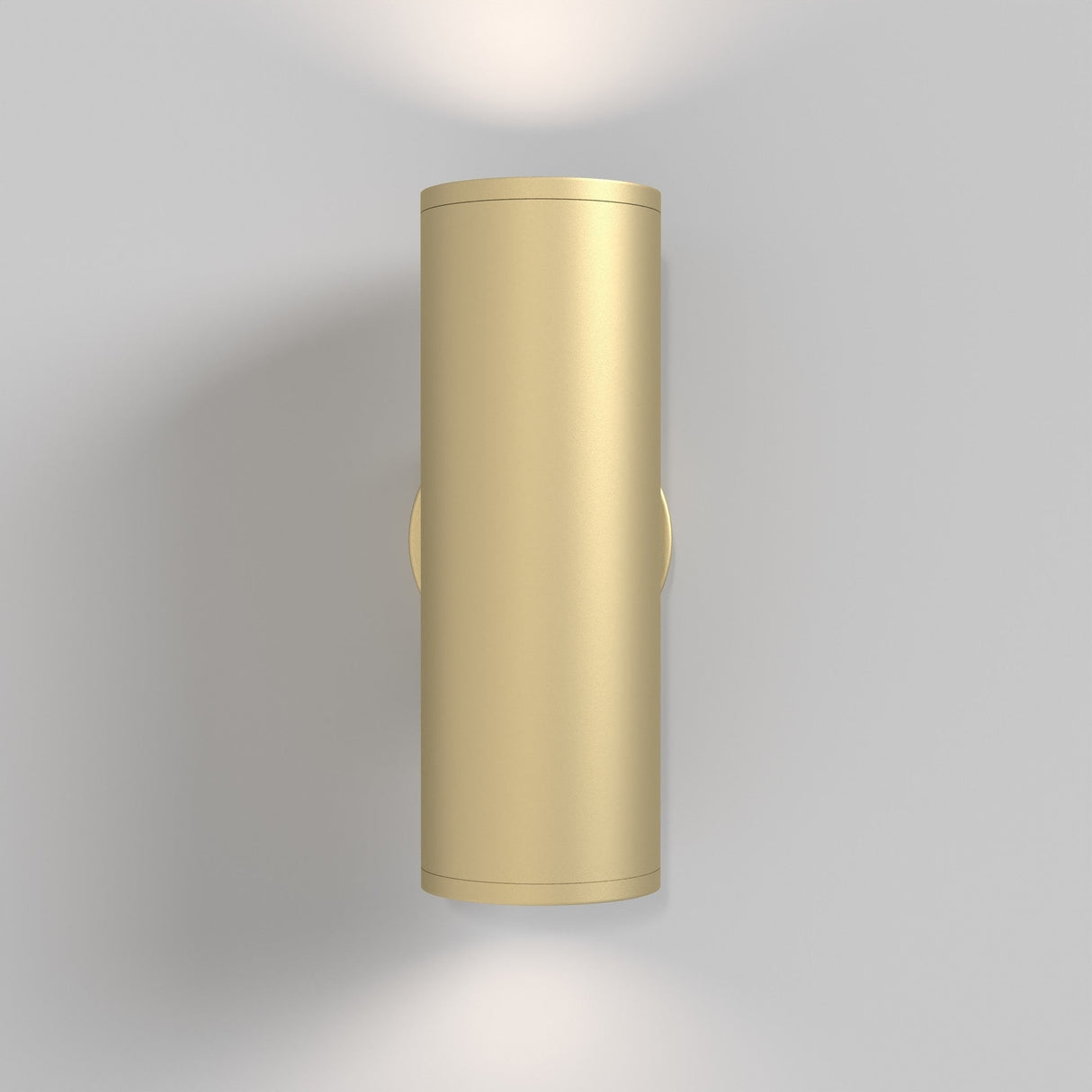 The FOCUS S Up & Down Wall Light in matte gold is a wall-mounted cylindrical sconce offering up and down lighting against a neutral gray backdrop.