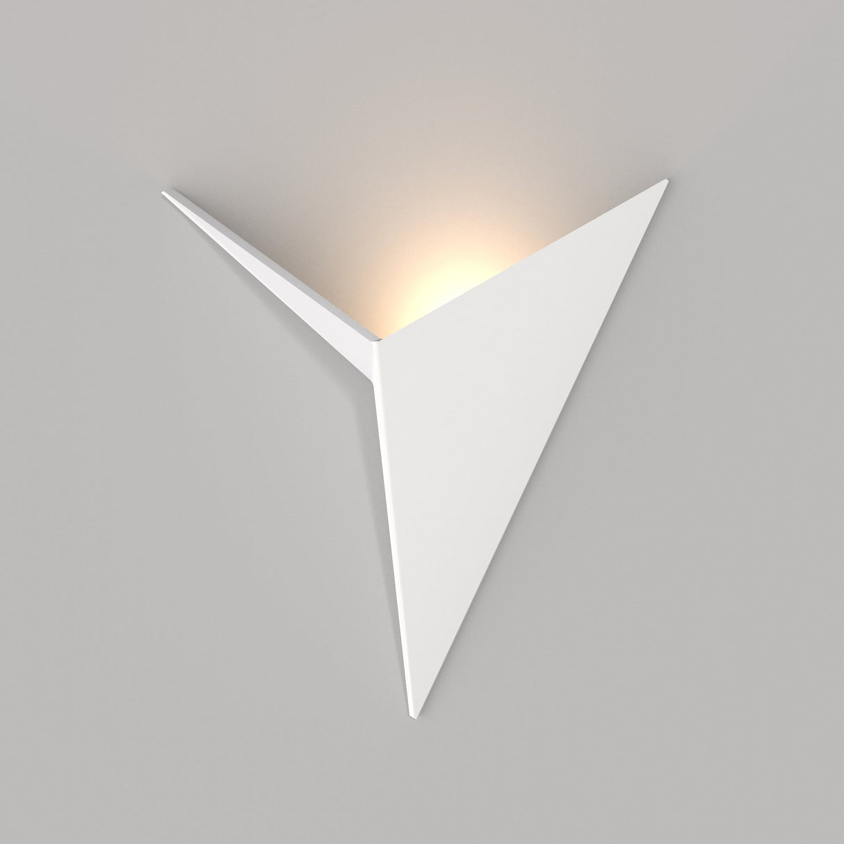 The Trame LED Wall Light 3W 3000K - White, with its modern triangular design, is mounted on a gray wall. This energy-efficient fixture emits a soft, warm glow from the top edge, creating a subtle ambient atmosphere ideal for minimalist interiors.