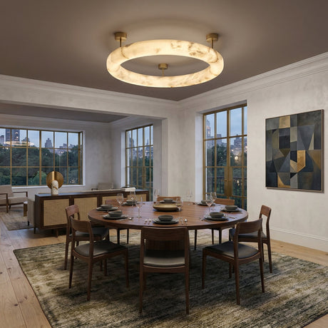 A modern dining room with a round wooden table for five and wooden chairs is illuminated by the Orbis Medium LED Alabaster Semi-Flush Ceiling Light – Soft White. Large windows, abstract art, and a view into the living area complete the space.
