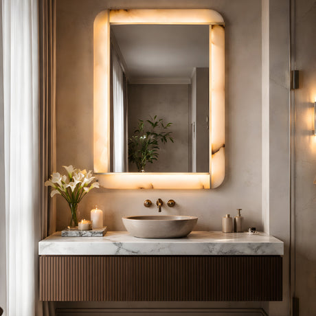 Niori Solviera LED alabaster rectangular wall mirror with brushed brass inlay and warm halo glow, mounted above a marble vanity with stone vessel sink.