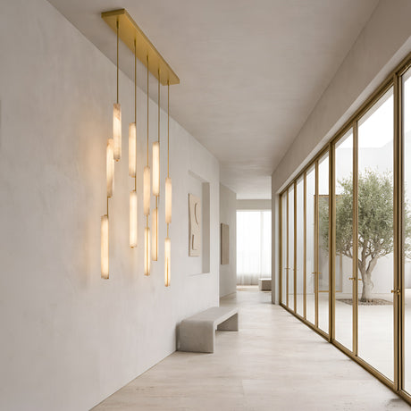 Selvara 10 Light Vertical Alabaster Linear Suspension in brushed brass with staggered alabaster batons, lit above a bench in a bright minimalist hallway.