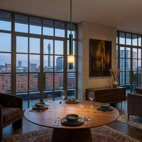 A modern dining area with a round wooden table for four, city views through floor-to-ceiling windows, contemporary decor, soft evening lighting, and the Solenne LED Alabaster Single Pendant Light in Dark Green & Polished Black overhead.