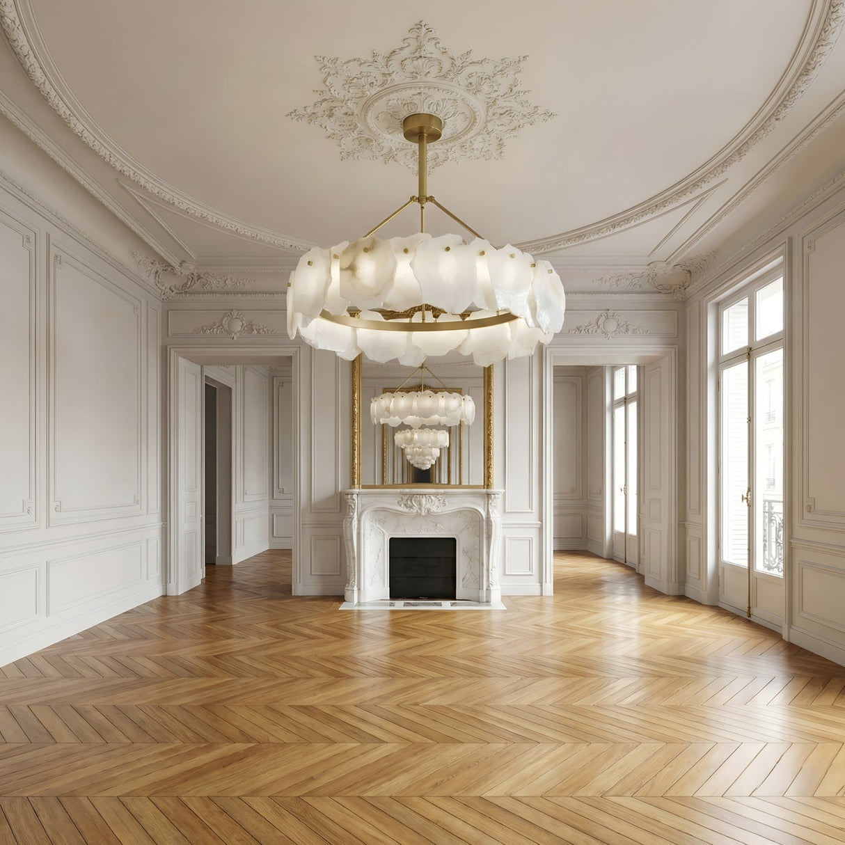 Elegant, empty room with ornate white walls, decorative fireplace topped by a large mirror reflecting the Marvion LED Small Petal Alabaster Chandelier (Soft White & Brass), light wood herringbone floors, and tall windows lining the right wall.