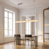 Niori Alba Small Alabaster Linear Chandelier in soft white glowing above a marble dining table with two black chairs in a bright period room.