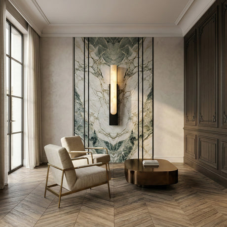 A modern, elegant living room features two beige armchairs, a bronze coffee table, a large marble accent wall with the Nerava LED Large Segmented Alabaster Wall Light (Soft White & Black), wood-paneled walls, and herringbone wood flooring.