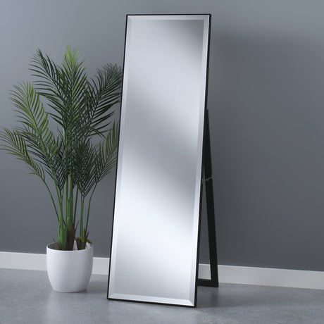 An Empyra Free Standing Mirror in black rests against a gray wall. A tall green plant, potted in white, complements the home decor on a light gray floor.