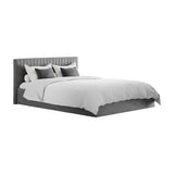 Berlin Ottoman double bed frame in silver velvet with a vertically channelled padded headboard and upholstered base, dressed with white bedding and grey cushions on a plain white background.