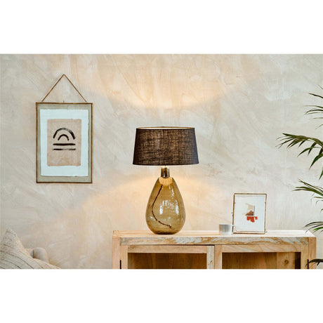 Baba Large Tall Recycled Glass Lamp Base in green with a black fabric shade, styled on a wooden sideboard beside framed art and a plant.