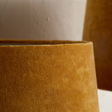 Close-up of the Batakha Medium tapered drum lampshade in dark ochre velvet with a natural linen lining showing as a pale band at the top rim.