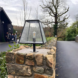 Large Contemporary Pillar Light in black steel with tapered glass shade and exposed bulb, mounted on a stone pier along an outdoor driveway.