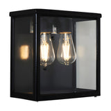 Contemporary Square Box Wall Lantern in black steel with clear glass panels, showing two exposed filament bulbs inside, set against a plain white background.