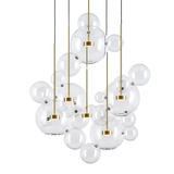 The Bubble 5 LED Glass Cluster Pendant Light - Gold showcases clusters of clear glass globes in varying sizes, suspended by gold rods and black cords for a floating, elegant look—perfect as a striking modern centerpiece.
