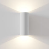 Parma paintable white cylindrical wall light installed, highlighting its up and down lighting capability and customisable finish for any decor.