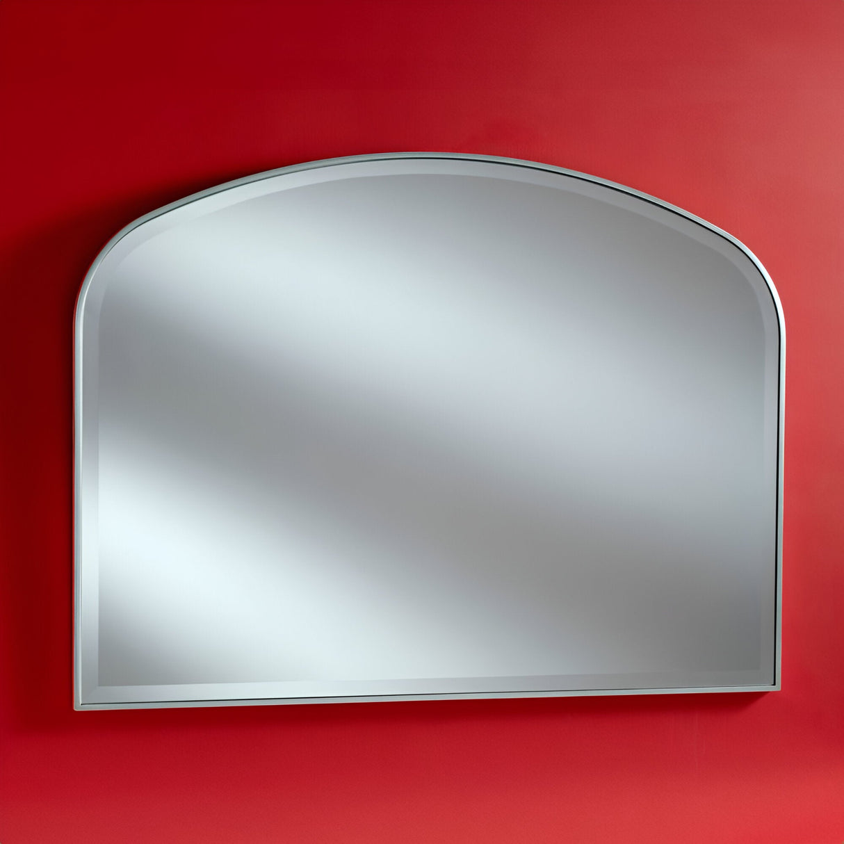 A Camden Overmantle Wall Mirror Silver, sized at 107x79cm, is mounted on a vibrant red wall. With its modern design and sleek silver frame, this mirror beautifully reflects light to create a bright and elegant appearance.