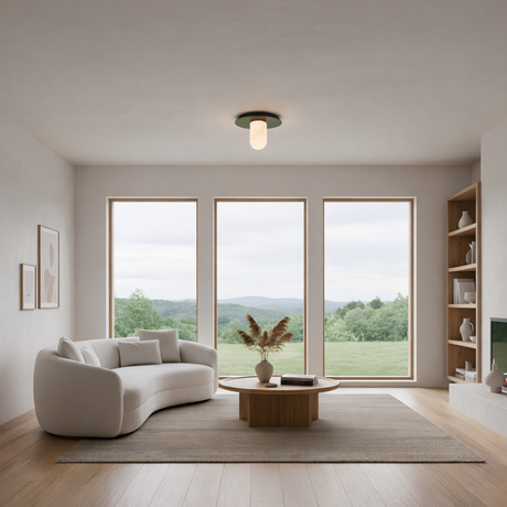 A modern minimalist living room with large windows, a white curved sofa, wood coffee table, neutral decor, light wood floors, and the Arvello 1 Light Dome Alabaster Semi-Flush Ceiling Light in soft white & matte black for gentle illumination.