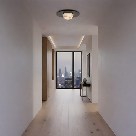 A modern hallway with light wood floors, white walls, and the Arvello 1 Light Wide Dome Alabaster Semi-Flush Ceiling Light in soft white and matte black overhead. A console table sits by floor-to-ceiling windows overlooking a city at dusk.