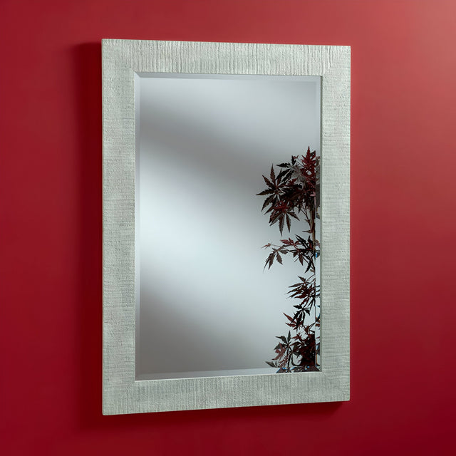The Zennia Rectangle Wall Mirror in white, featuring a textured silver frame, perfectly elevates your home decor by reflecting red maple leaves against a smooth red wall.