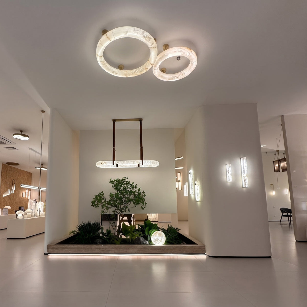 Orbis Extra Large LED Alabaster Semi-Flush Ceiling Light in soft white, two overlapping alabaster rings with brushed brass mounts, shown installed above a showroom display.