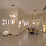 Caldera Large Alabaster Wall Light in matt black, shown among multiple vertical alabaster wall lights and pendants in a modern showroom with dining area.
