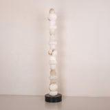 Stratalux LED floor lamp with a tall stacked column of alabaster spheres and discs on a round matt black base, shown against a plain light background.
