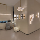 Caldera Large Alabaster Wall Light in matt black, shown among multiple wall lights in a showroom, elongated alabaster panel split by a black metal band with warm integrated LED glow.