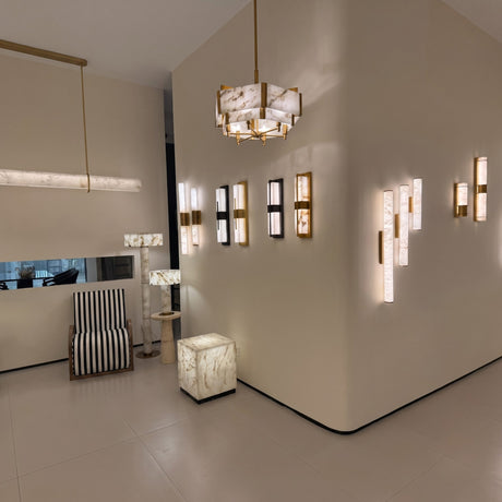 Caldera Large Alabaster Wall Light in matt black, shown among multiple wall lights in a showroom, elongated alabaster panel split by a black metal band with warm integrated LED glow.
