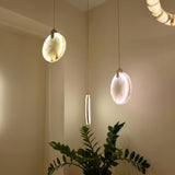Luna LED Alabaster Disc Pendant Light in brushed brass, illuminated circular alabaster discs with brass bracket suspension, shown hanging in a room alongside similar pendants and a leafy plant.