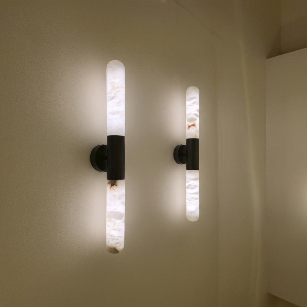Averin LED Alabaster Wall Light in Matte Black, two illuminated vertical alabaster columns with black centre bracket, shown mounted in pairs on a neutral wall.