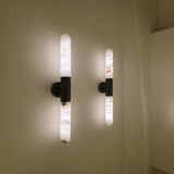 Averin LED Alabaster Wall Light in Matte Black, two illuminated vertical alabaster columns with black centre bracket, shown mounted in pairs on a neutral wall.