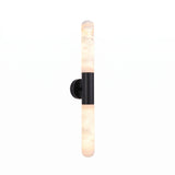 Averin LED Alabaster Wall Light in Matte Black, featuring two vertical alabaster columns joined by a round black centre bracket, shown lit against a plain white background.