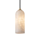 Velmora slim cylindrical pendant light with a tall alabaster shade in soft white, brass ceiling plate and black flex cord, shown lit against a plain white background.