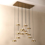 Aurevia 14-light LED linear chandelier with rectangular brushed brass canopy and staggered alabaster-and-brass domed drops, shown against a plain light wall.