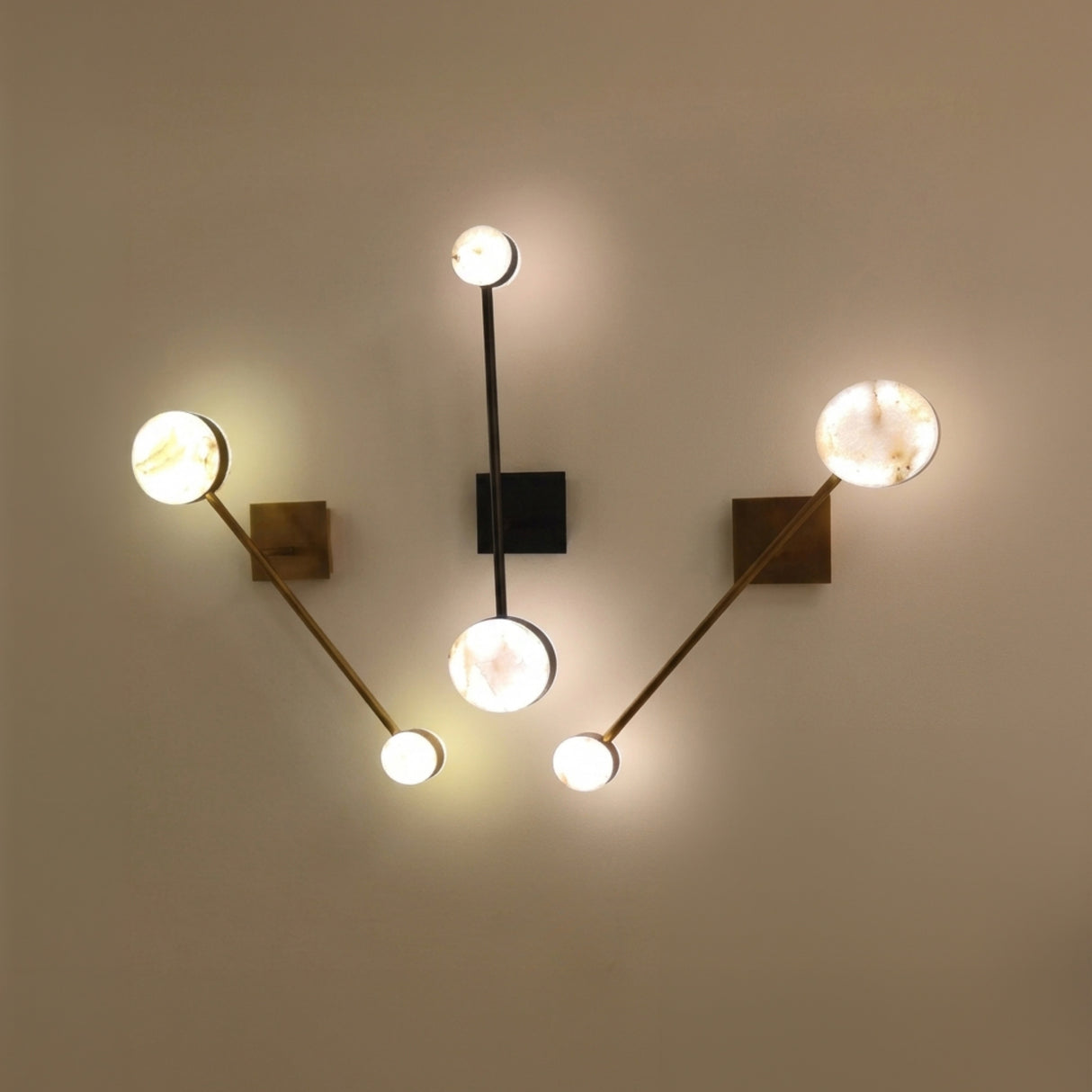 Marvello LED Twin Sphere Alabaster Wall Light in brushed brass, shown with matching multi-arm sconces featuring glowing alabaster discs on a neutral wall.