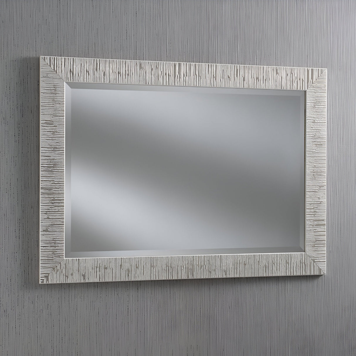 The Radix Rectangle Wall Mirror - White/Silver features a textured, light frame that exudes modern luxury. When hung against a vertically striped gray wall, it reflects a blurred, neutral background and adds a contemporary look to any room.