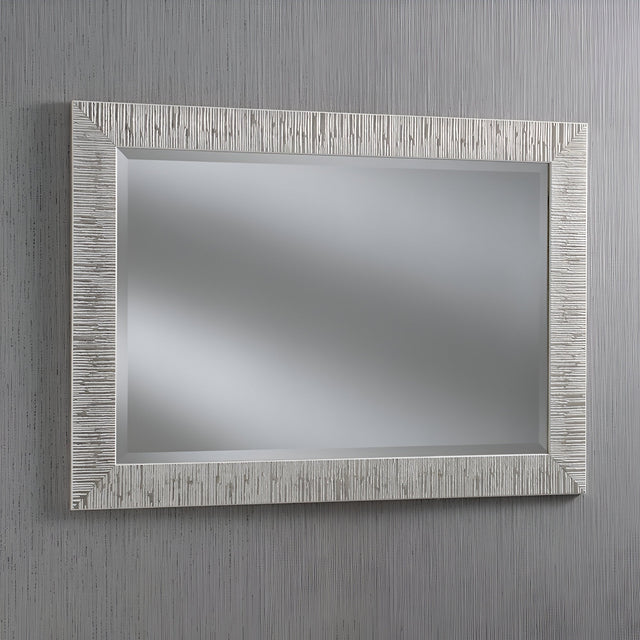 The Radix Rectangle Wall Mirror - White/Silver features a textured, light frame that exudes modern luxury. When hung against a vertically striped gray wall, it reflects a blurred, neutral background and adds a contemporary look to any room.