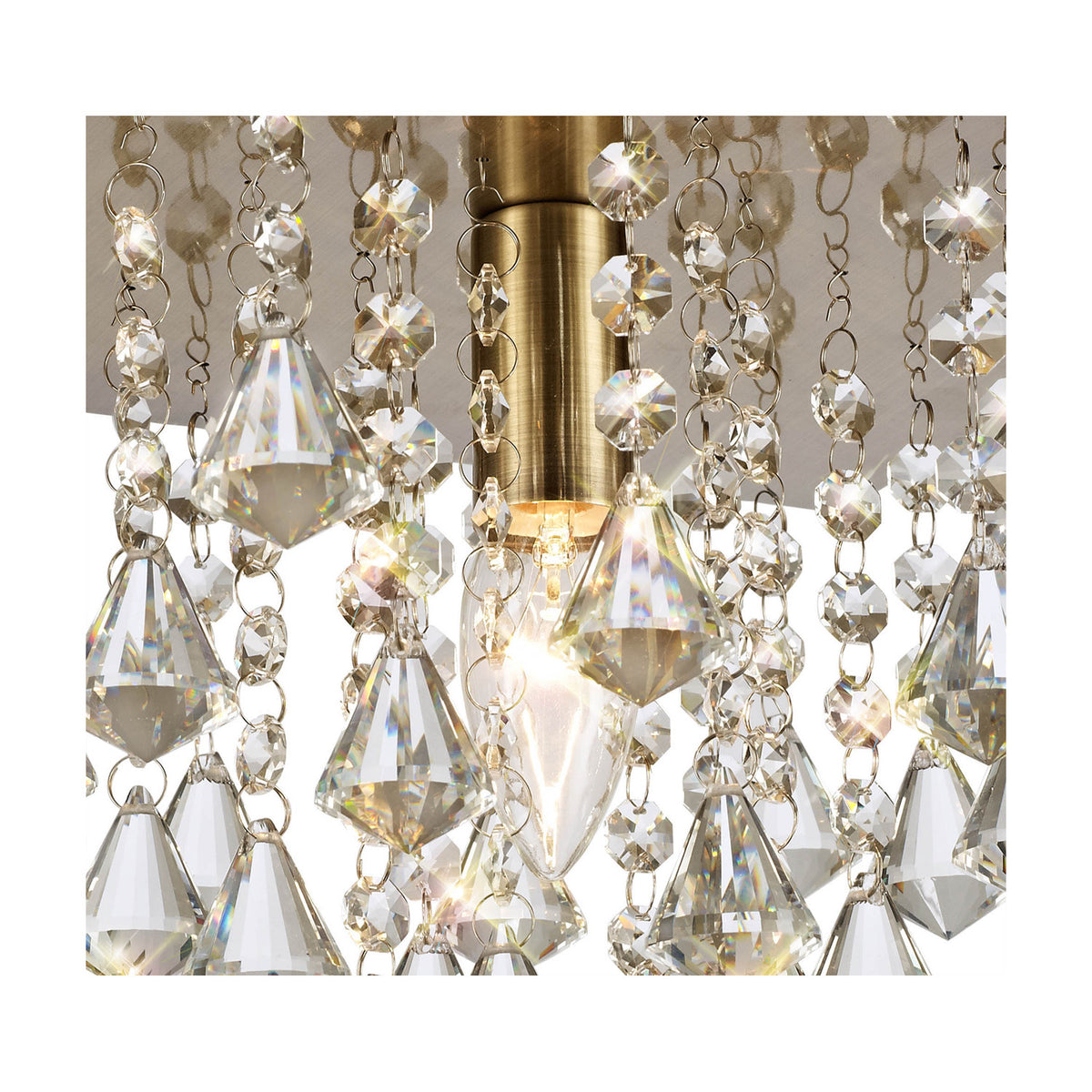 Close-up of the Acton E14 round flush ceiling light, 25cm, showing an antique brass fitting with a lit candle bulb surrounded by hanging clear crystal strands and faceted drops.