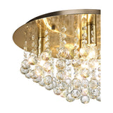 Close-up of the Acton 5 Light E14 Round Flush Ceiling Light 46cm in antique brass, showing clear crystal spheres cascading from a brass ceiling plate on a white background.