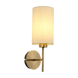 Carlton 1 Light E27 Wall Light in antique brass with round wall plate and cylindrical cream fabric shade, shown against a plain white background.