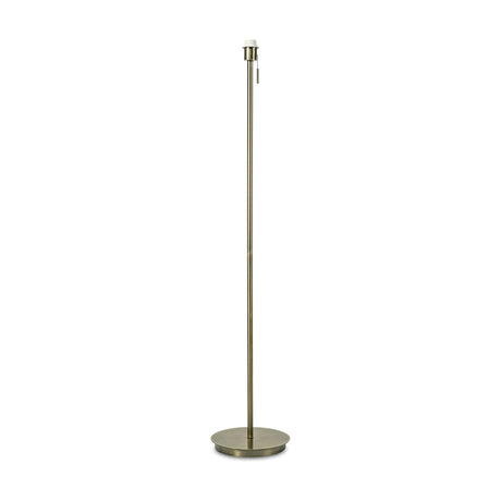 Carlton E27 floor lamp in antique brass, 28cm round flat base with a slim iron upright, pull switch and E27 lampholder at the top, shown shadeless on a plain white background.