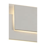 Close-up of the Kiania Rectangular Wall Light in sand white, showing the flat square panel with a soft warm white LED glow along its top and bottom edges against a plain background.