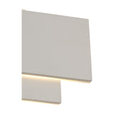 Close-up of the Kiania Rectangular Wall Light in sand white, showing the tiered rectangular panels with a warm white LED strip glowing along the frosted diffuser edge.