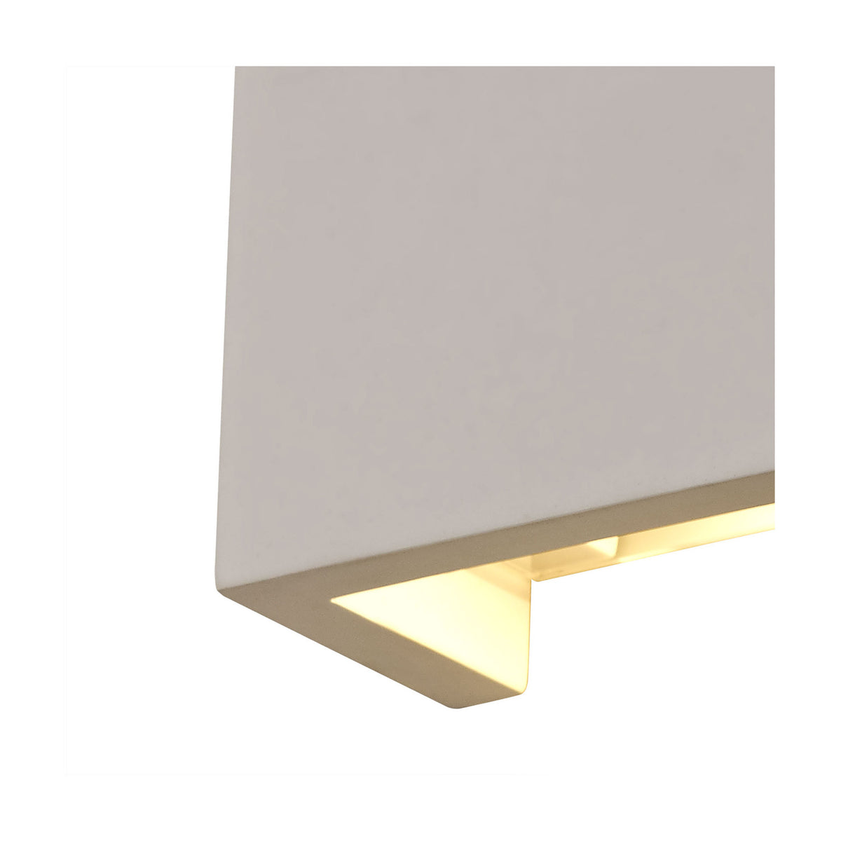 Close-up of the Alina square wall light in white paintable gypsum, showing the angled underside edge where warm white LED light spills out, shown against a plain white background.
