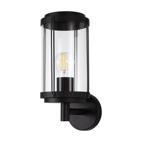 Reva E27 IP44 wall light in black, cylindrical clear polycarbonate shade with visible filament bulb, mounted on a round black wall bracket, shown on a plain white background.