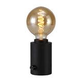Delp E27 Table Lamp in sand black, a compact cylindrical base with rotary dimmer, holding an amber globe bulb with visible spiral filament on a plain white background.