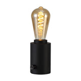 Delp E27 Table Lamp 70mm in sand black, a compact cylindrical iron base with a rotary dimmer knob, shown fitted with a glowing spiral-filament ST64 bulb on a plain white background.