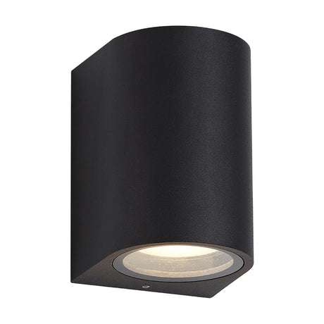 Tomar Curved Outdoor Wall Light in sand black, a compact curved aluminium fixture with clear front glazing and a single illuminated GU10 lamp, shown on a plain white background.